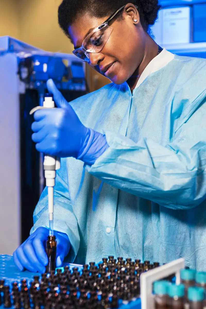 A laboratory scientist in protective gear pipetting samples
